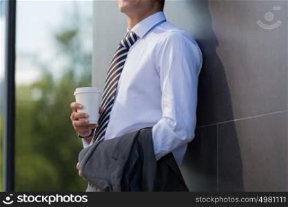 Unrecognizable businessman drinking coffee on the street near office building