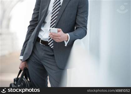 Unrecognizable businessman in suit using smartphone in office