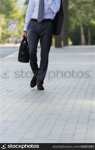 Unrecognizable businessman walking on the street near office building