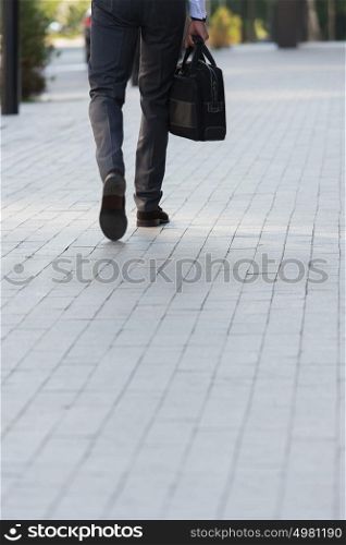 Unrecognizable businessman walking on the street near office building