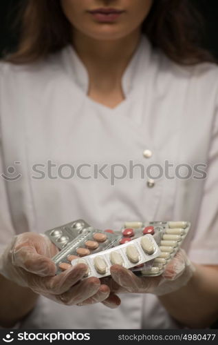 Unrecognizable doctor holding a stack of many different pills