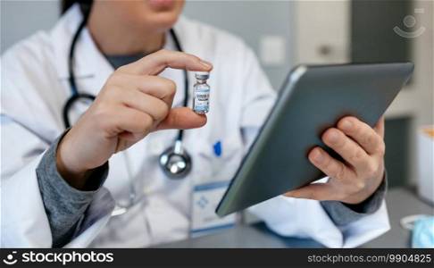 Unrecognizable female doctor doing online consultation with tablet showing covid-19 vaccine