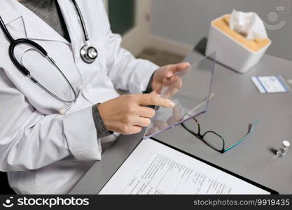 Unrecognizable female doctor working with transparent tablet in her office. Unrecognizable female doctor working with transparent tablet