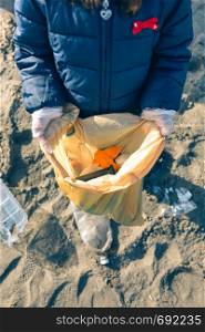 Unrecognizable girl showing bag full of garbage collected from the beach. Girl showing garbage collected from the beach
