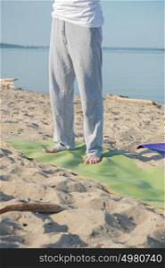 Unrecognizable man on yoga mat at the beach