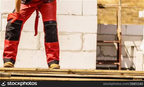 Unrecognizable person on construction site wearing protective worker red black pants trousers. Person wearing red worker trousers
