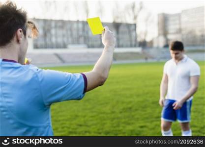 unrecognizable referee showing yellow card