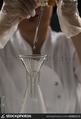 Unrecognizable science professional pipetting liquid into the glass cuvette