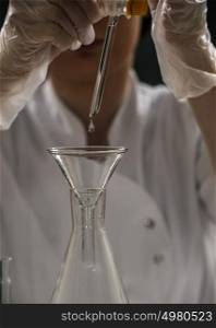 Unrecognizable science professional pipetting liquid into the glass cuvette