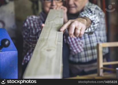 Unrecognizable senior couple working in a carpentry workshop. Selective focus on hand. Senior couple in a carpentry