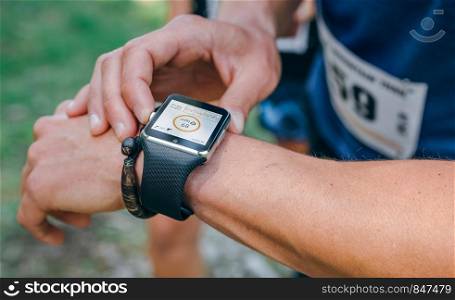 Unrecognizable sportsman looking at a smartwatch outdoors. Sportsman looking a smartwatch
