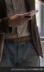 Unrecognizable stylish businessman texting on the phone in office