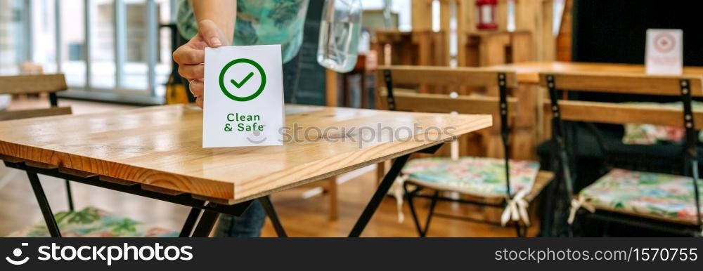 Unrecognizable waitress placing Clean and Safe sign on coffee shop table. Unrecognizable waitress placing sign on coffee shop tables