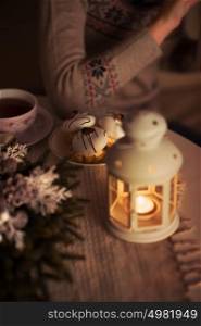 Unrecognizable woman drinking tea. Candle cake and tea cup on table, Cozy warm light