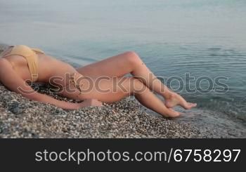 unrecognizable woman lying in bikini on the beach by the sea