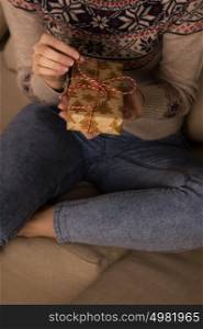 Unrecognizable woman opening Christmas gift at home