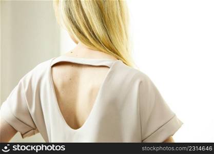 Unrecognizable woman presenting fashionable pink top with hole detail on her back.. Woman showing hole detail on back of top