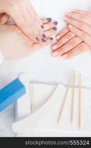 Unrecognizable woman presenting her beautiful painted gel hybrid nails next to professional manicure set. Nail care concept.. Woman presenting her beautiful painted gel hybrid nails