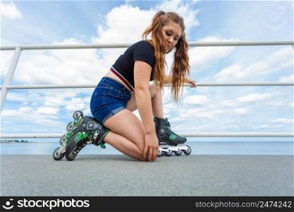 Unrecognizable woman putting on roller skates. Female being sporty having fun during summer in city. Woman putting roller skates on