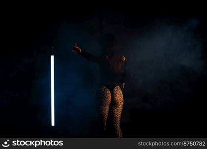 Unrecognizable woman shows a gesture - wait in smoky dark studio. Sexy outfit - thong bodysuit and leopard pantyhose. Lady with pumped up buttocks. High quality photo. Unrecognizable woman shows a gesture - wait in smoky dark studio. Sexy outfit - thong bodysuit and leopard pantyhose. Lady with pumped up buttocks