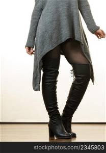 Unrecognizable woman wearing gray long top sweater tunic, black tights. Stylish, autumnal outfit.. Woman wearing gray long top sweater tunic