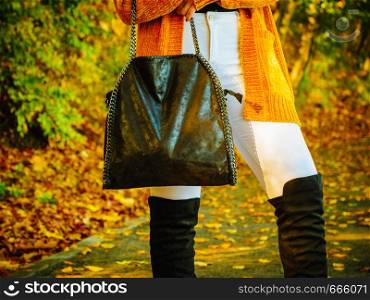 Unrecognizable woman wearing long orange warm cardigan sweater. Autumnal fashion, autumn season styled outfits. Female having a walk in park. Woman wearing orange autumn cardigan outdoor