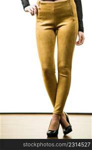 Unrecognizable woman wearing tight leggings pants mustard yellow brown well fitting skinny trousers. Woman wearing mustard tight pants