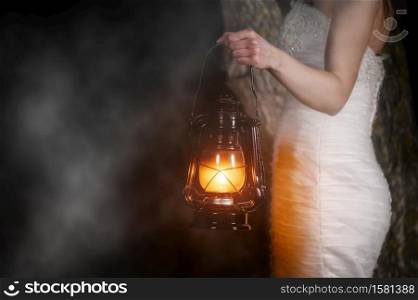 Unrecognizable Woman with Vintage Lantern Outside at Night. Young woman in white long dress walking in night wood. High quality photo. Unrecognizable Woman with Vintage Lantern Outside at Night. Young woman in white long dress walking in night wood.