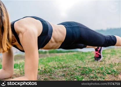 Unrecognizable young female athlete training doing plank outdoors. Female athlete training doing plank