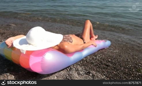 unrecognizable young woman sunbathing lying on a pool raft by the sea