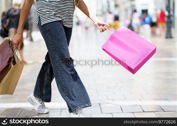 Unrecognizable young woman with shopping bags in the street.. Unrecognizable woman with shopping bags in the street.
