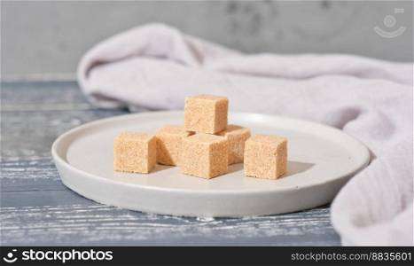 unrefined brown cane sugar cubes on cement plate. stack of natural sweetener for healthy meal.. unrefined brown cane sugar cubes on cement plate. stack of natural sweetener for healthy meal