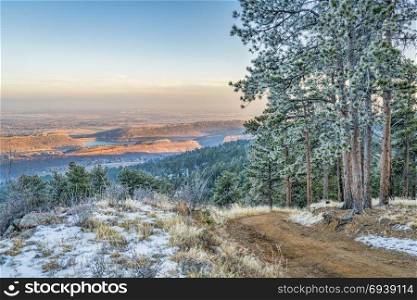 unset view of plains, foothills and lake in northern Colorado, a view from Towers Trail in Horsetooth Mountain Park with pine trees covered by frost