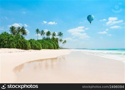 Untouched tropical beach. Empty vacation island coast with palm trees and hot air balloon in the sky.