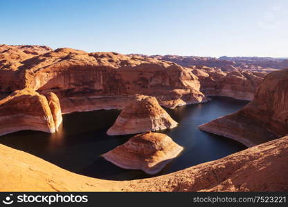 Unusual natural background. Reflection Canyon on Lake Powell, Utah, USA. Inspiring hiking scene-man resting on the beautiful sunset point.