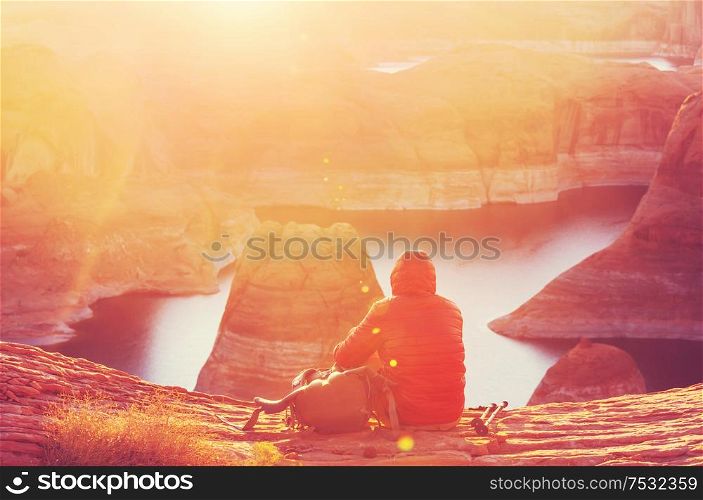 Unusual natural background. Reflection Canyon on Lake Powell, Utah, USA. Inspiring hiking scene-man resting on the beautiful sunset point.