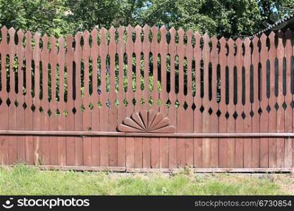 Unusual wooden fence of the yard of the rural