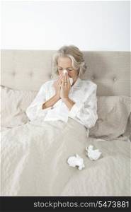 Unwell senior woman blowing nose in bed
