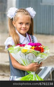 Up portrait of a seven-year school girl with a bouquet of flowers