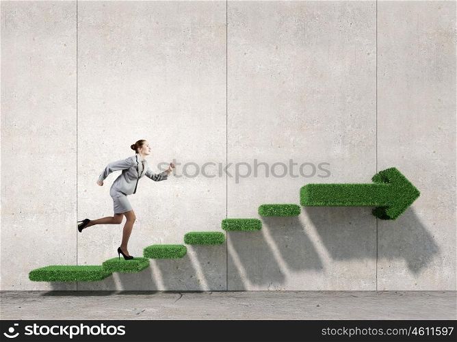 Up the career ladder. Businesswoman with suitcase running on green grass staircase