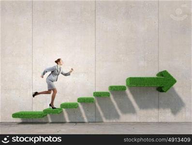 Up the career ladder. Businesswoman with suitcase running on green grass staircase