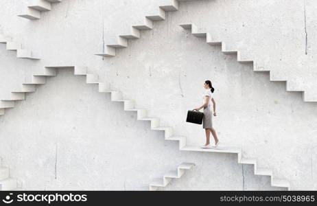 Up the career ladder. Businesswoman with suitcase stepping up stone staircase