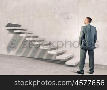Up the career ladder. Young businessman reaching up staircase as symbol of growth and progress