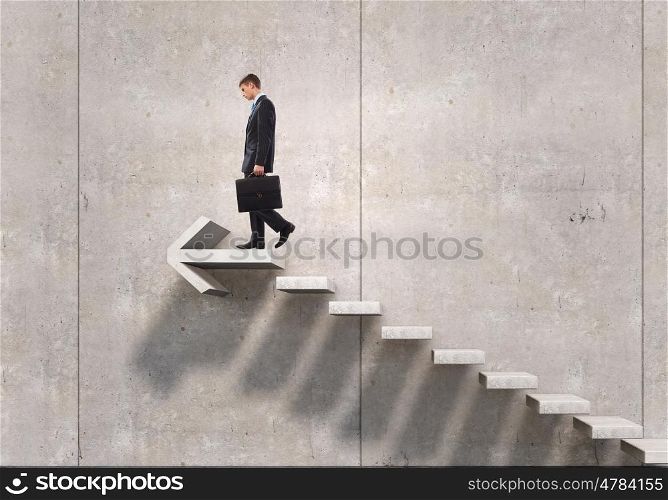 Up the career ladder. Young businessman reaching up staircase as symbol of growth and progress
