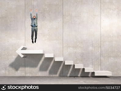 Up the career ladder. Young businessman reaching up staircase as symbol of growth and progress