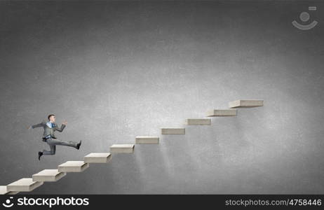 Up the career ladder. Young businessman running up on staircase representing success concept