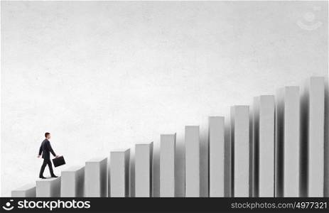 Up the career ladder. Young businessman walking up on growing graph representing success concept