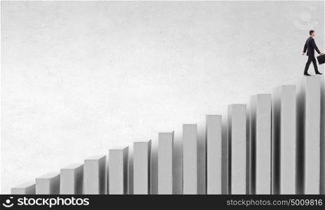 Up the career ladder. Young businessman walking up on growing graph representing success concept