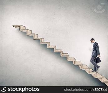Up the career ladder. Young businessman walking up on ladder representing success concept