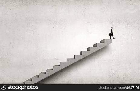 Up the career ladder. Young businessman walking up on staircase representing success concept